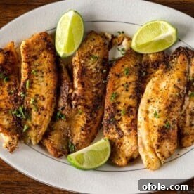 Pan Seared Tilapia on a serving tray with fresh lime wedges, a simple seafood dinner.