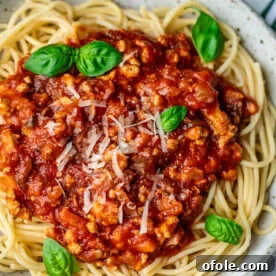 Spaghetti in a bowl topped with chicken Bolognese sauce, a rich and hearty meal.