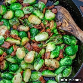 Pan-fried Brussels sprouts with bacon in a black skillet, a savory side dish.