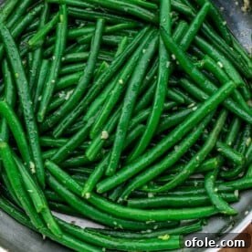 Square image of bright green beans coated in garlic butter.