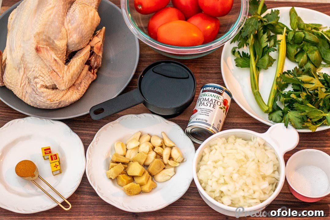 A vibrant selection of ingredients for African chicken stew, including tomatoes, onions, ginger, garlic, and fresh herbs, arranged on a rustic chopping board.