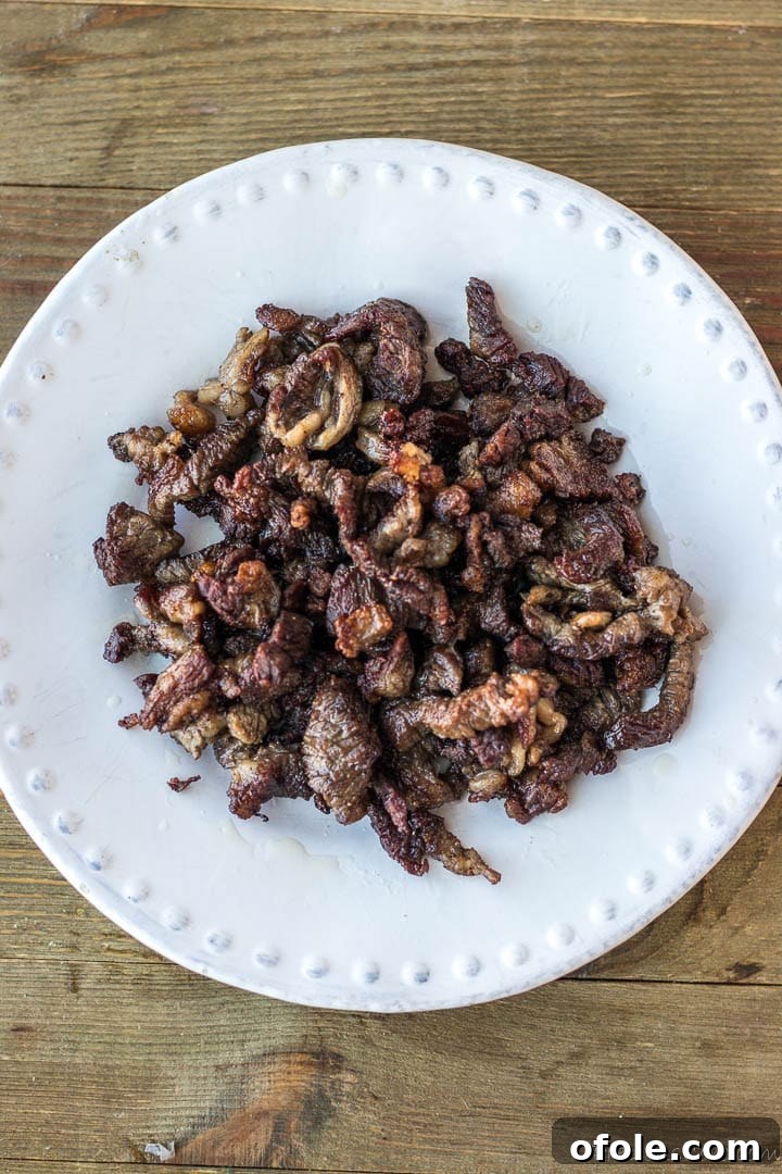 Perfectly browned beef slices resting on a plate after cooking.